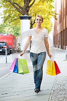 Happy Woman Carrying Shopping Bags On Sidewalk