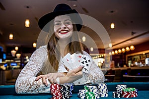 Happy woman in casino with poker chips and cards