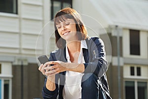 Happy woman with cellphone sitting outside