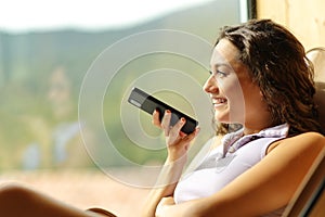 Happy woman on a chair dictating message on phone