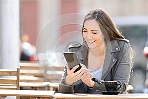 Happy woman checking phone in a coffee shop