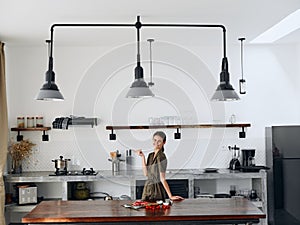 Happy woman chef smile with teeth in Stylish kitchen interior with natural elements in wood and stone design with fresh