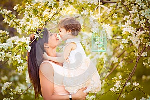 Happy woman and child in the blooming spring garden.Child kissi