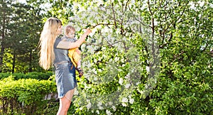 Happy woman and child in the blooming spring garden. Mothers day holiday concept