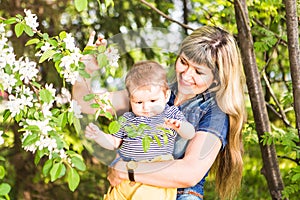 Happy woman and child in the blooming spring garden. Mothers day holiday concept