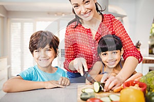 Happy woman with children chopping vegetables at home photo