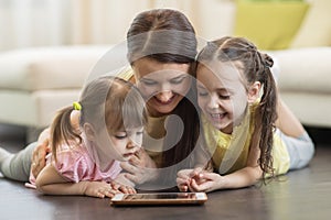 Happy woman and children using digital tablet on floor at home