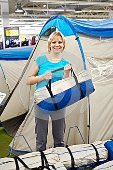 Happy woman chooses tent camp in store leisure goods