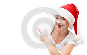 Happy woman with christmas hat peeking through a hole torn in w