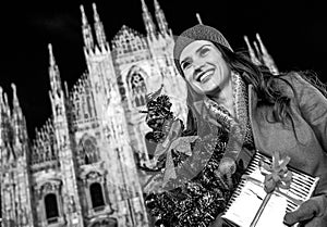 Happy woman with Christmas tree in Milan looking into distance