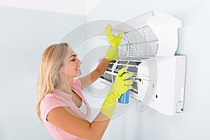 Happy Woman Cleaning The Air Conditioner