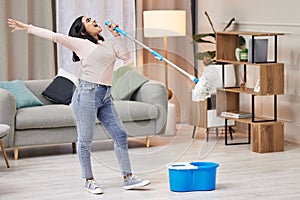 Happy, woman and cleaning floor by singing with mop by dance to relax at home for hygiene routine . Smile, housewife and