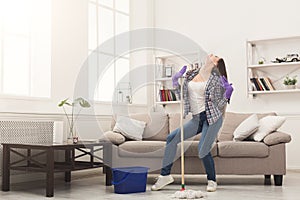 Happy woman cleaning home with mop and having fun