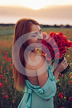 Happy woman with closed eyes holding bouquet of poppies