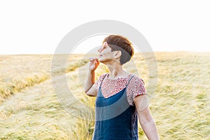 A happy woman with closed eyes relaxing in wheat field on sunset. Breathe of freedom. Positive emotions feeling life