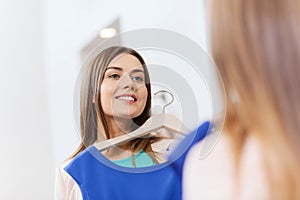 Happy woman with clothes at clothing store mirror