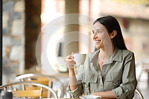 Happy woman in a coffee shop drinking contemplating