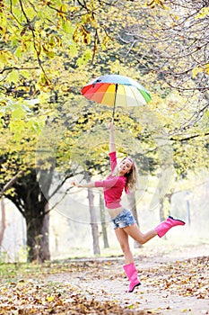 Happy woman with colorful umbrella in autumn park