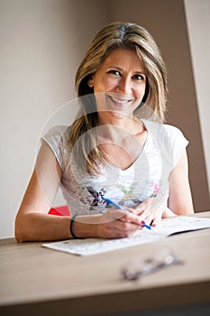 Happy woman completing crossword puzzles