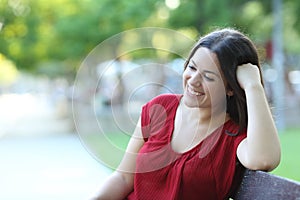 Happy woman contemplating on a bench in a park