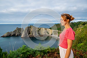Happy woman contemplating views in a coast on summer
