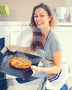 Happy woman cooking pizza at home