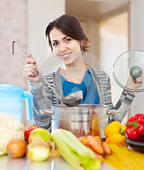 Happy woman cooking veggie soup