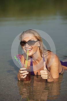 Happy woman with cool drink in the water