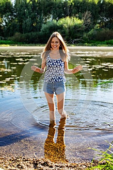Happy woman cools off in the refreshing water of forest river