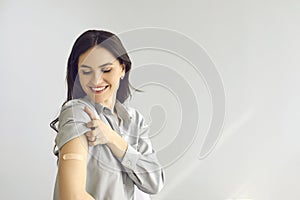 Happy woman on copy space background shows arm after receiving flu or Covid-19 vaccine