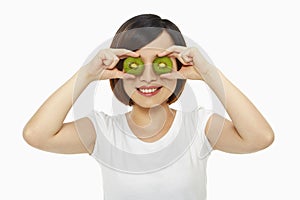 Happy woman covering her eyes with a kiwi