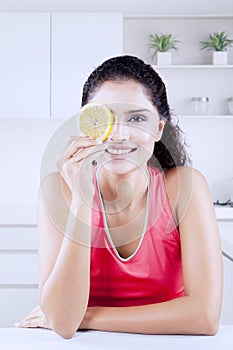 Happy woman covers her one eye with an orange