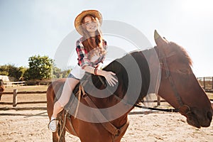 Happy woman cowgirl riding horse on ranch