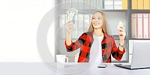 Happy woman with credit card and dollars cash working online on computer earning money