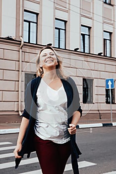 Happy woman at the crosswalk. A woman in summer clothes crossing the street at a pedestrian crossing, road safety.