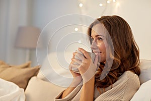 Happy woman with cup of coffee in bed at home