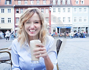 Happy woman with curly blond hair with coffee latte macchiato