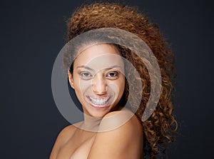 Happy woman with curly hair smiling on gray background