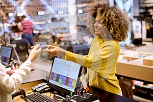 Happy woman customer paying with credit card in fashion showroom