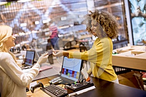 Happy woman customer paying with credit card in fashion showroom