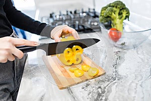 Close up of woman hands cut pepper for cooking vegetables salad at the kitchen