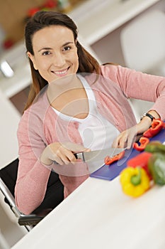 Happy woman cutting vegetables in kitchen