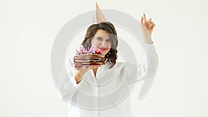 a happy woman dancing with a birthday cake with candles on a white background