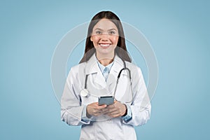 happy woman doctor in white coat with cellphone