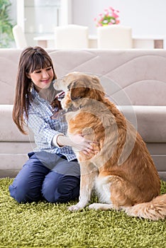 The happy woman dog owner at home with golden retriever