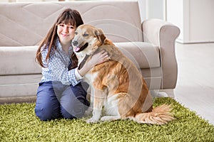 The happy woman dog owner at home with golden retriever