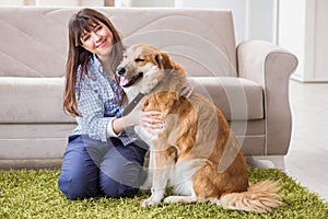 The happy woman dog owner at home with golden retriever