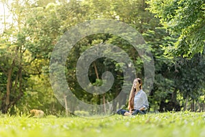 Happy woman doing meditation and relaxing in the park. Meditation in nature. Concept of healthy lifestyle and relaxation