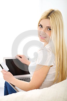 Happy woman doing online shopping at home . Close- up of a hand holding a credit card next to a laptop