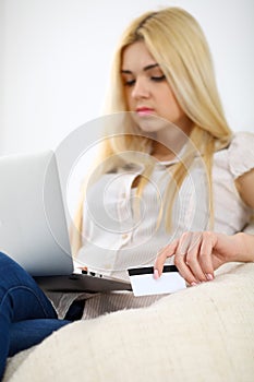 Happy woman doing online shopping at home . Close- up of a hand holding a credit card next to a laptop